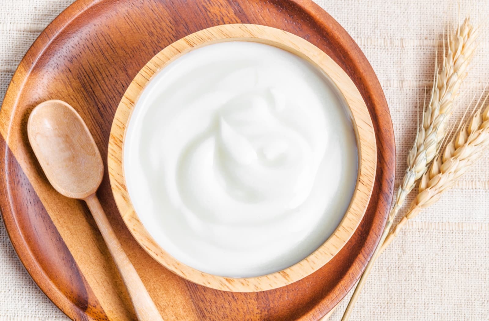 Plain Greek yogurt sits in a rustic wooden bowl.