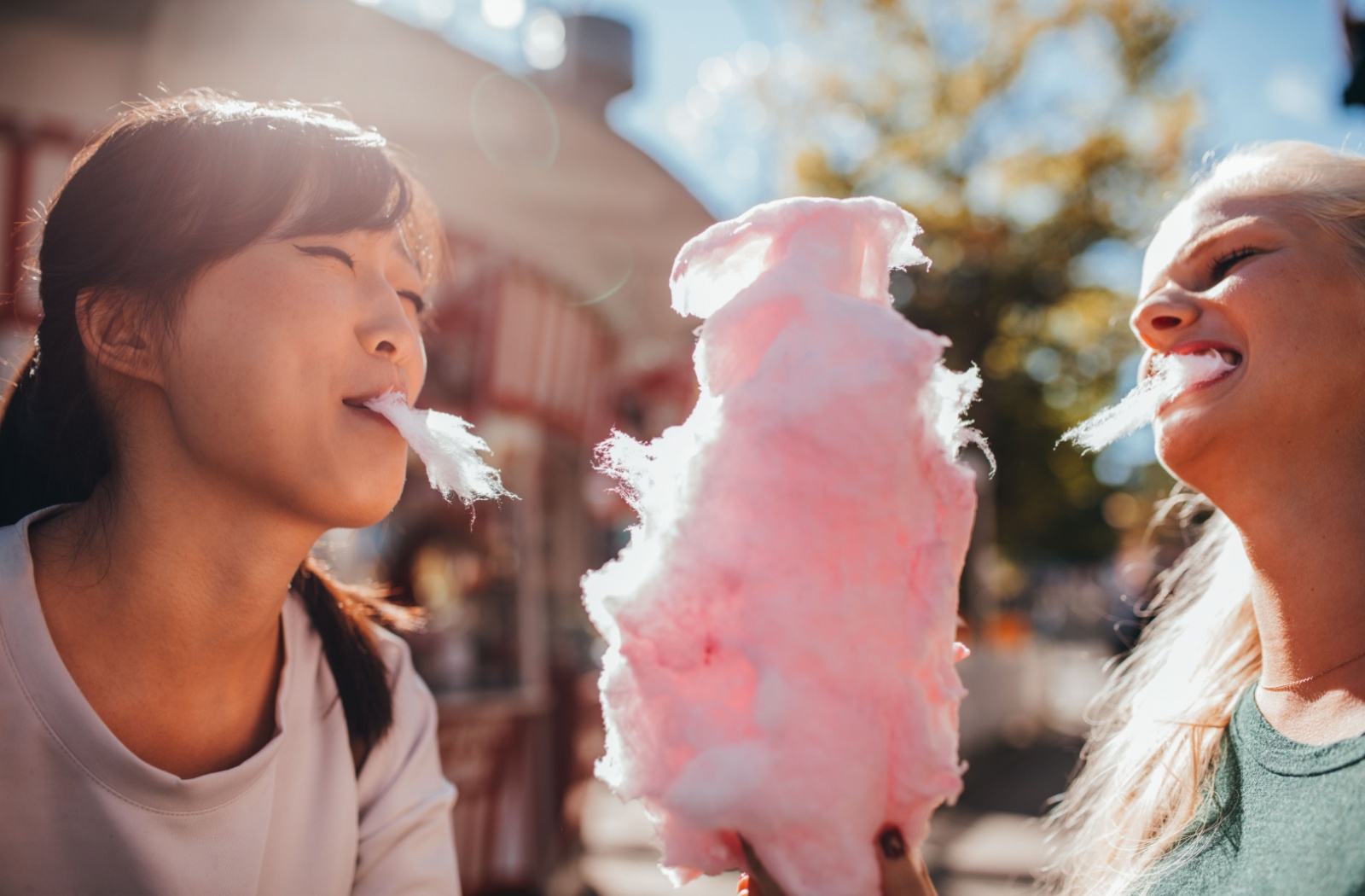 Two people sharing pink cotton candy.