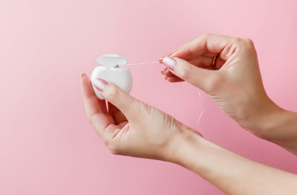 A hand pulling floss out of a container