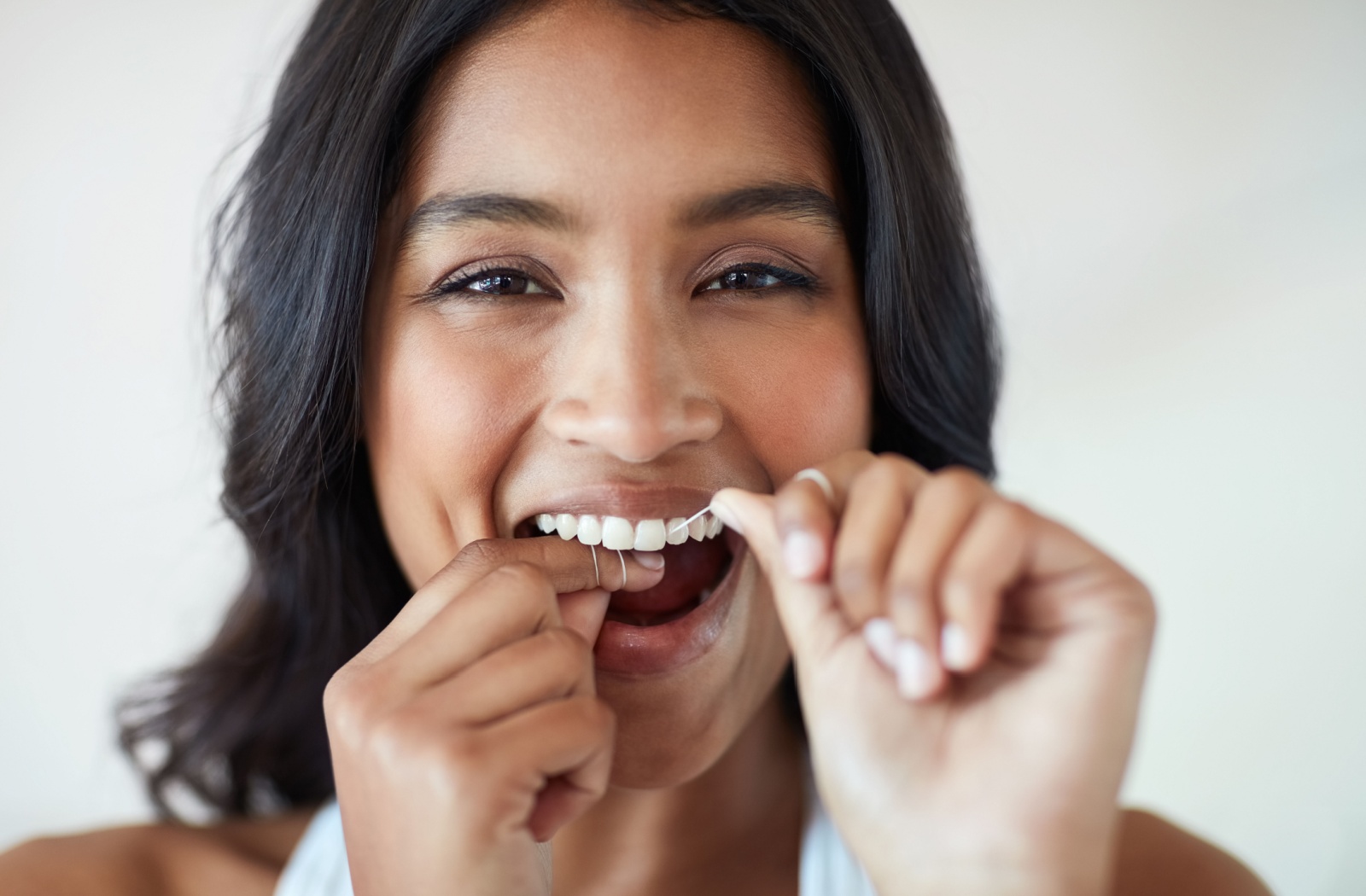 A close up of a person flossing their teeth.
