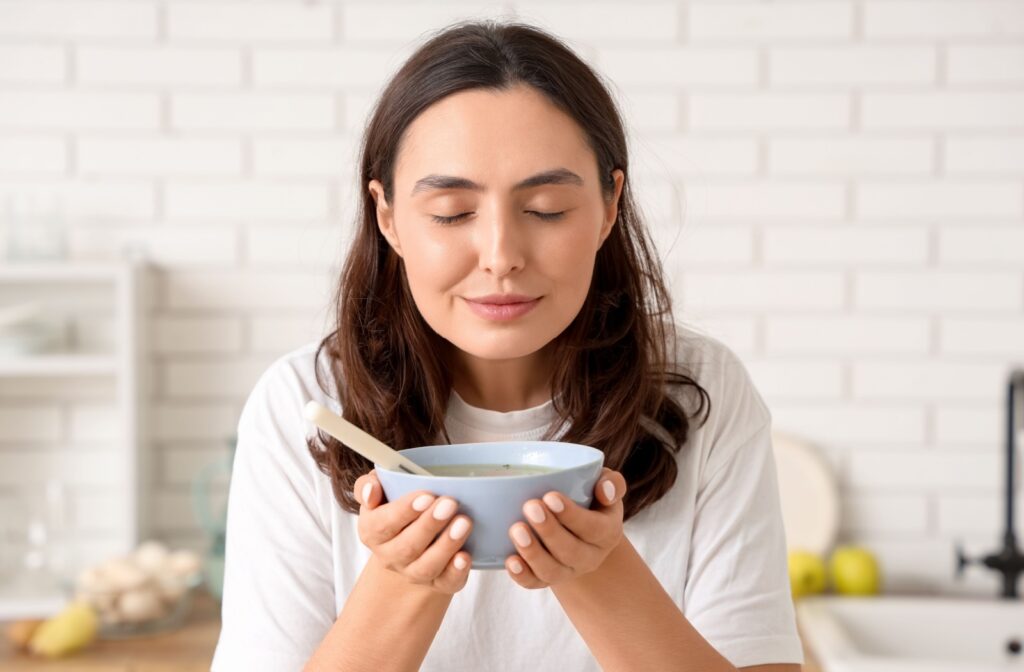 A person holding a warm bowl of soup, showing what they're eating after wisdom tooth removal.